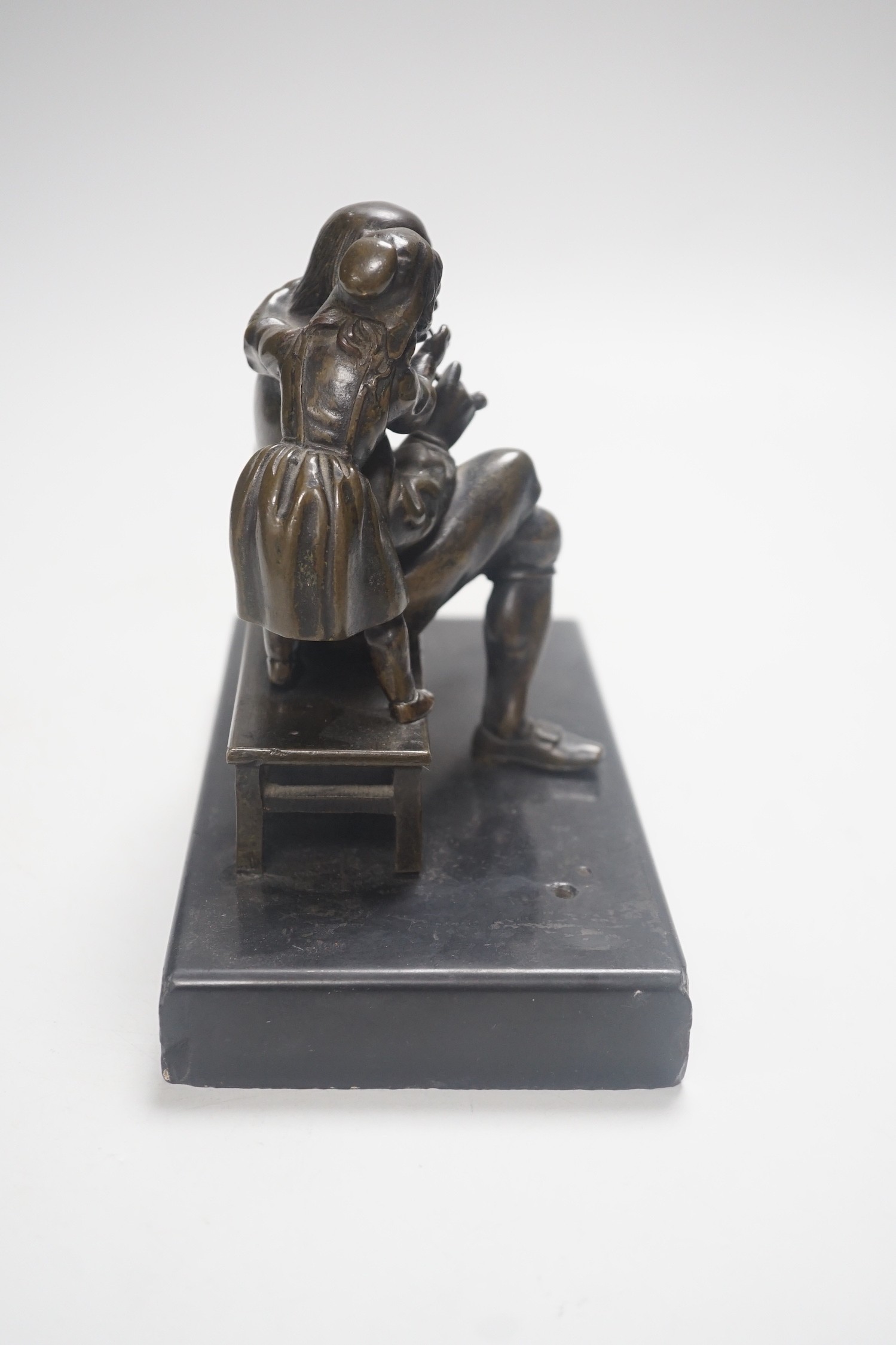 A 19th century bronze group of a gentleman smoking a pipe and a girl, on slate base 18.5cm wide